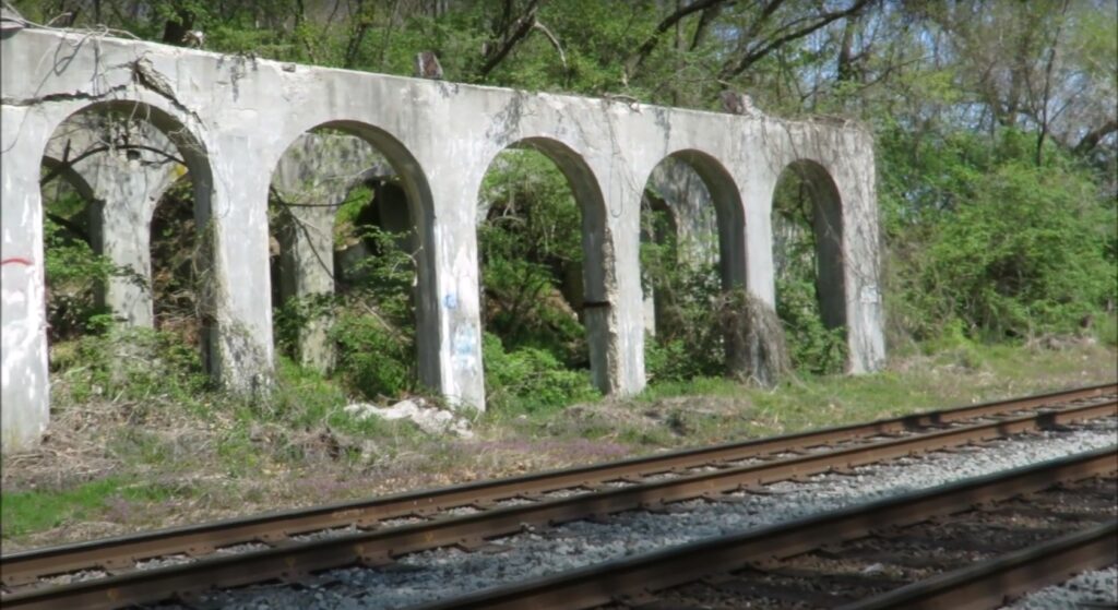 a railroad and ruins of a building in a forest