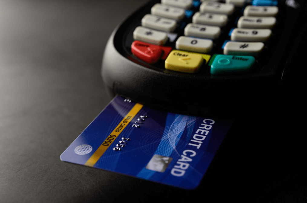 A credit card inserted into a payment terminal with colorful keys.