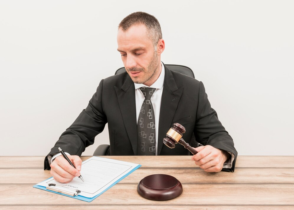 Man holding a gavel and writing on a document